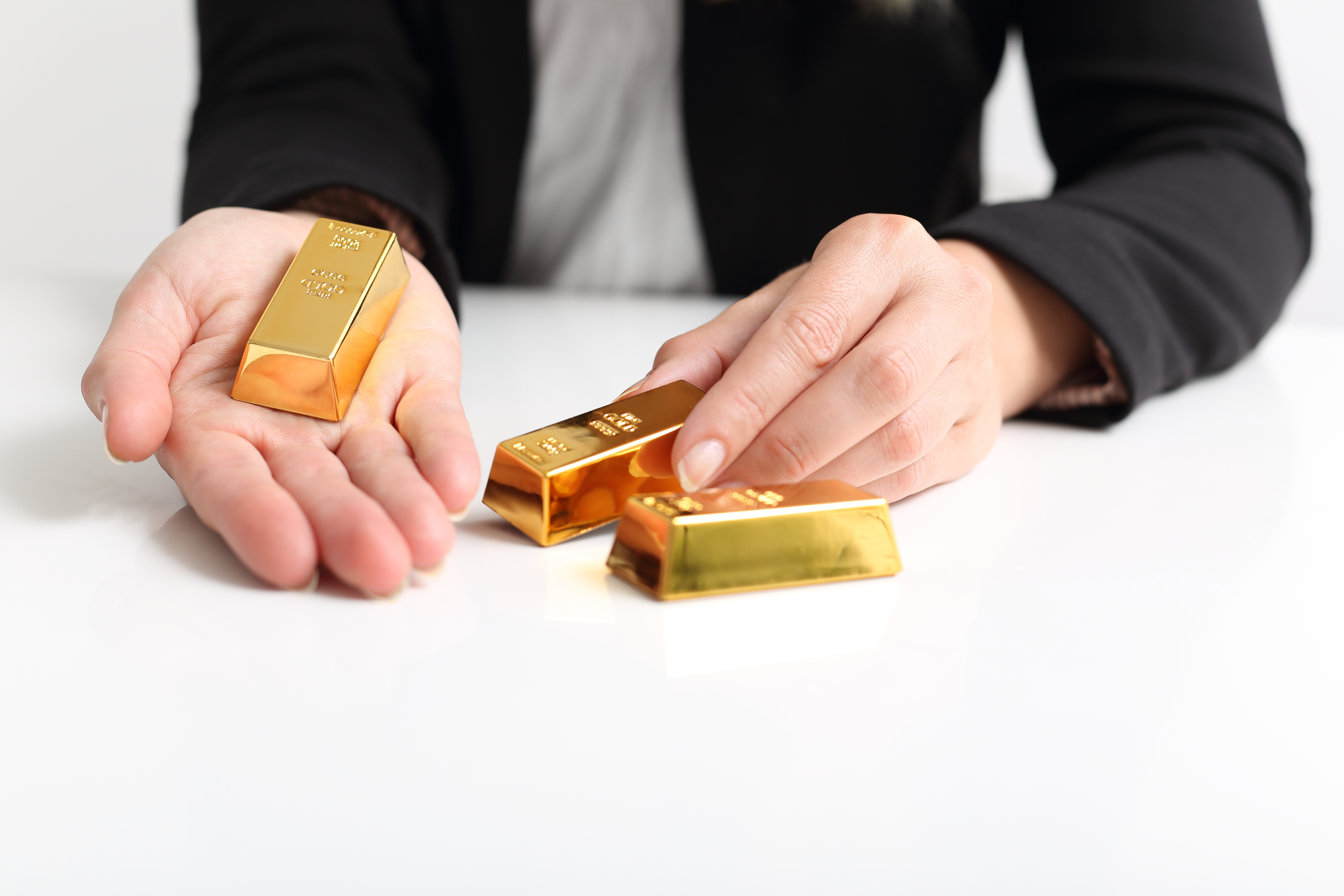 Person in business suit holding small gold bars in their hands.
