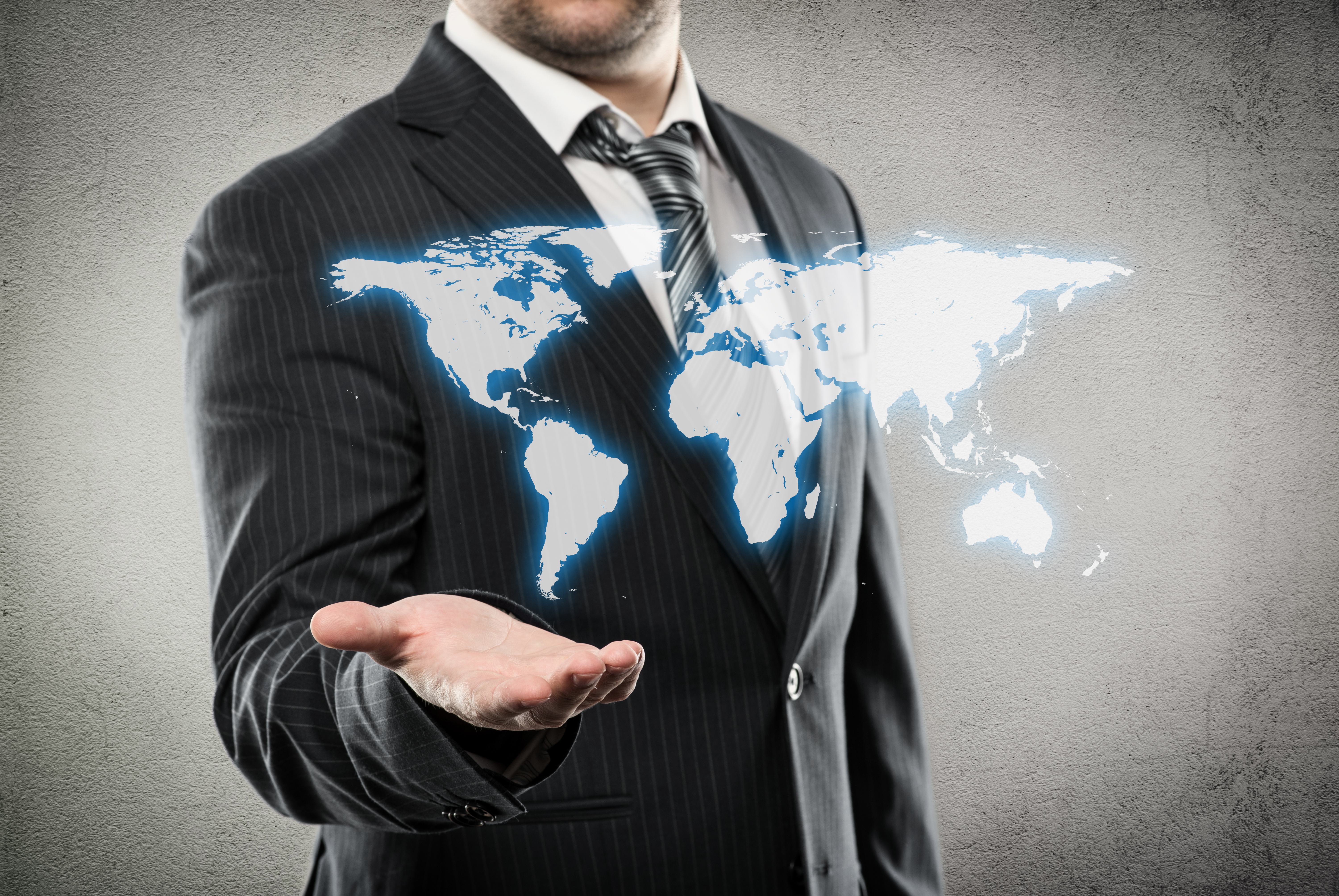 Person in pinstriped suit and tie "holding" hologram-like image of a world map.