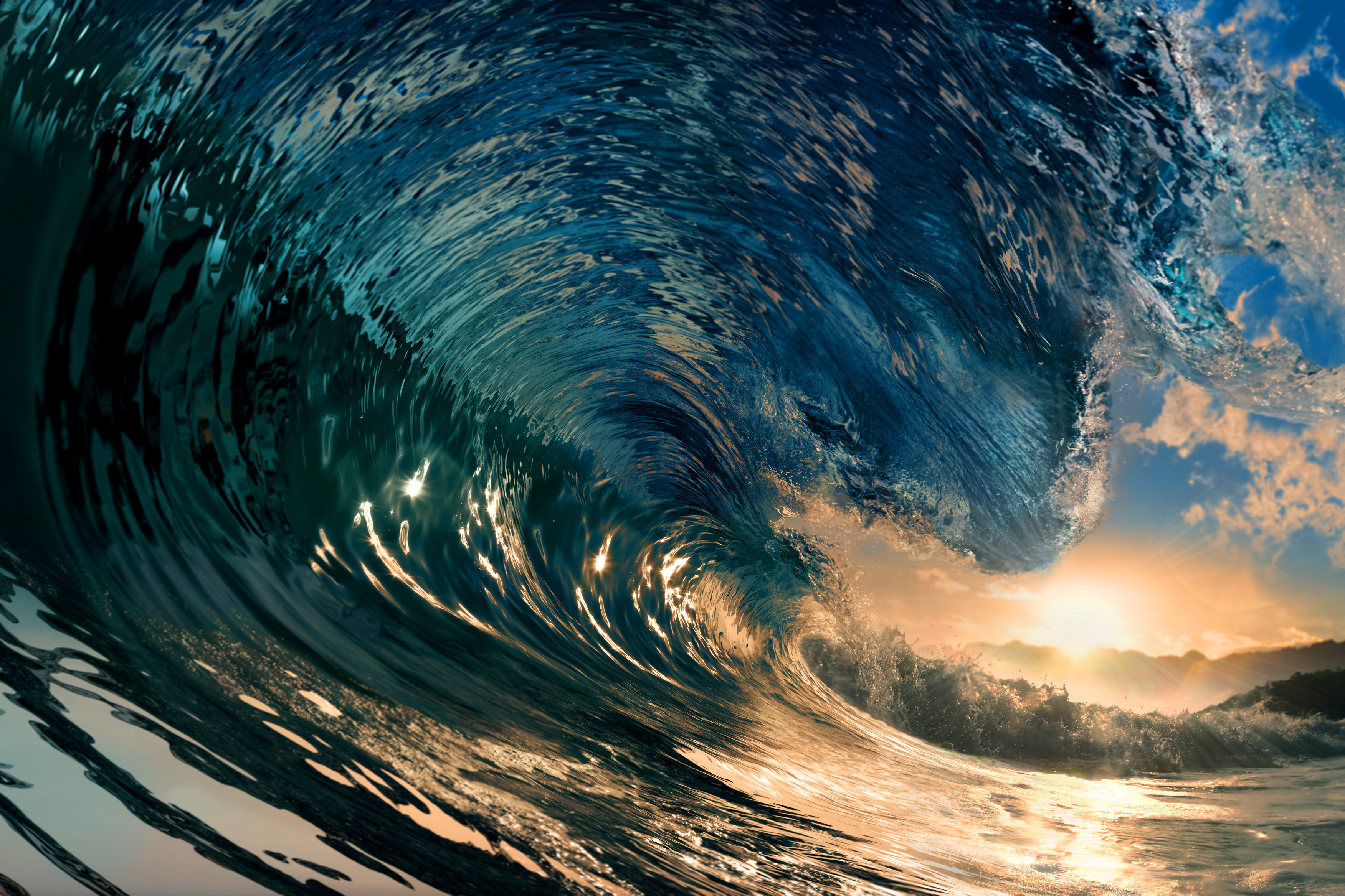 Large blue wave curling toward shore at sunset.