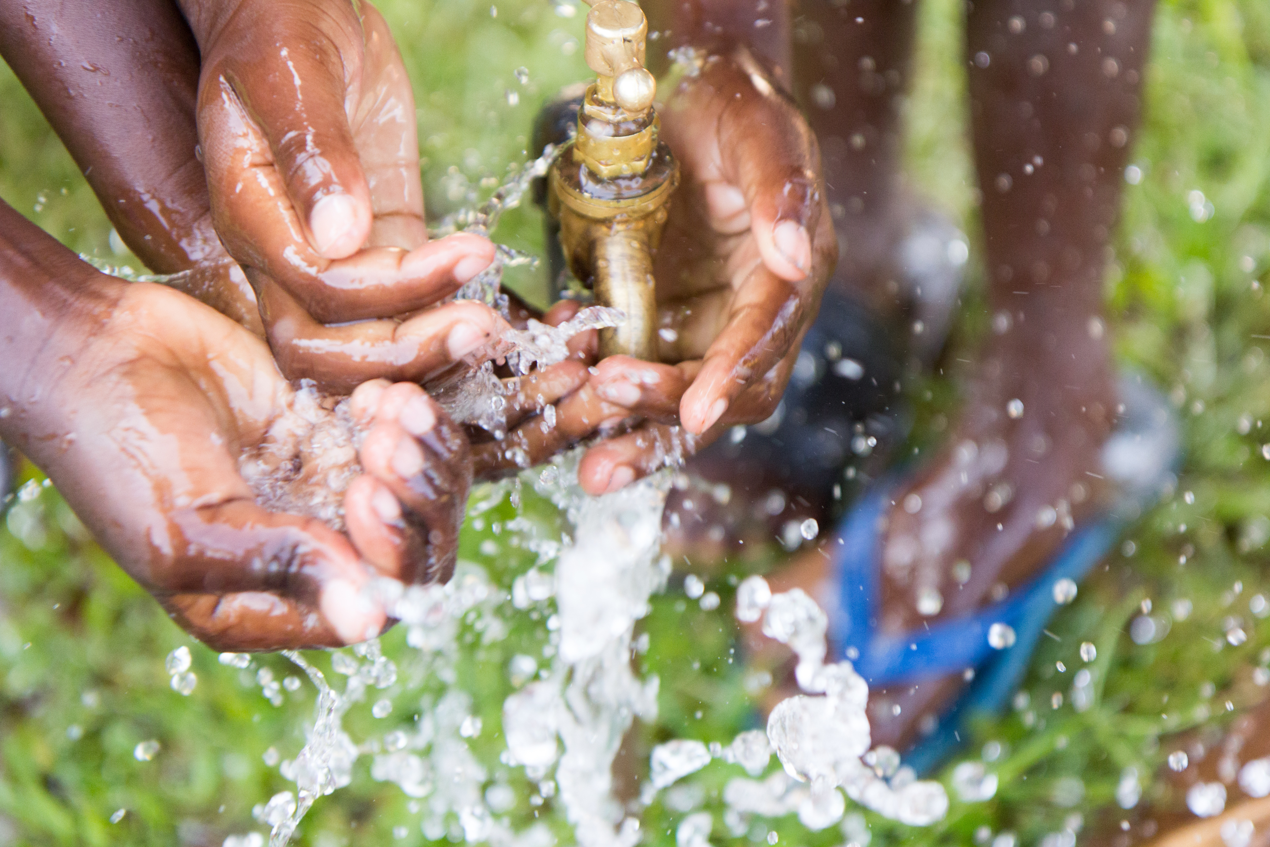 The Markets Corner: Water. Children wash their hands under an outdoor tap.