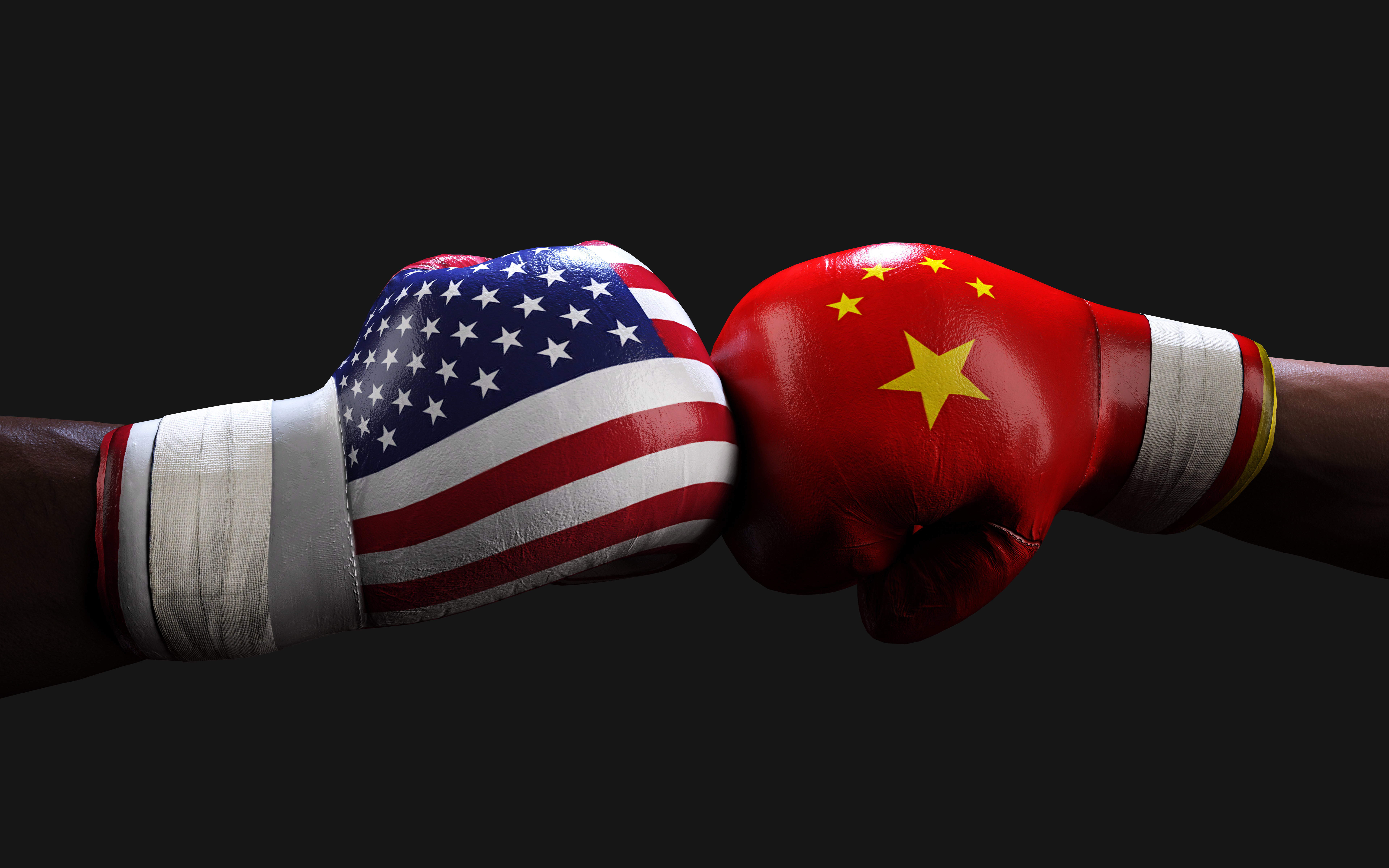 Hands of opposing boxers. Hand on left wears boxing glove with U.S. flag patter; hand or right wears boxing glove with Chinese flag pattern.