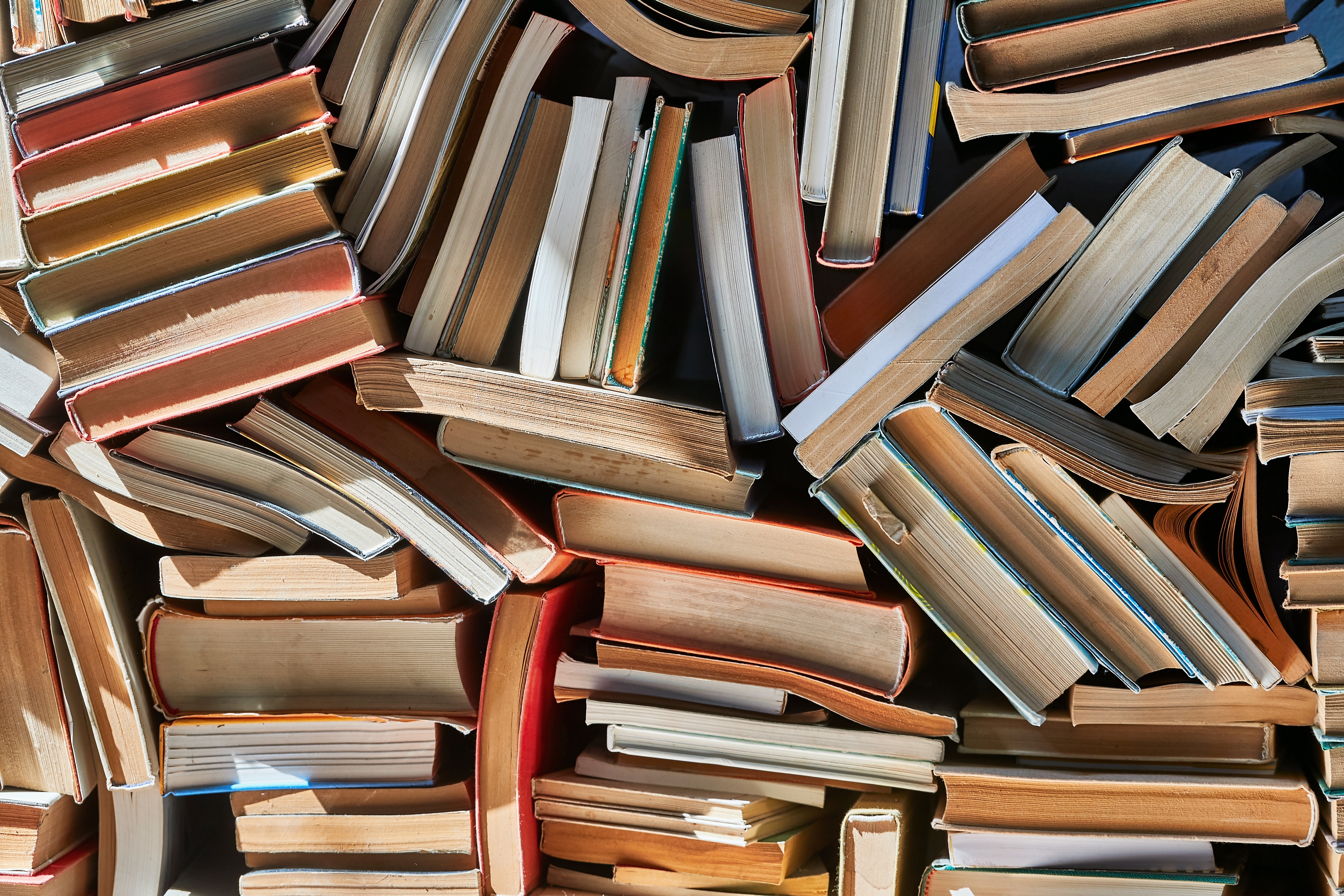 Photo: a haphazard stack of books, lit by sunlight, filling the entire field of view.