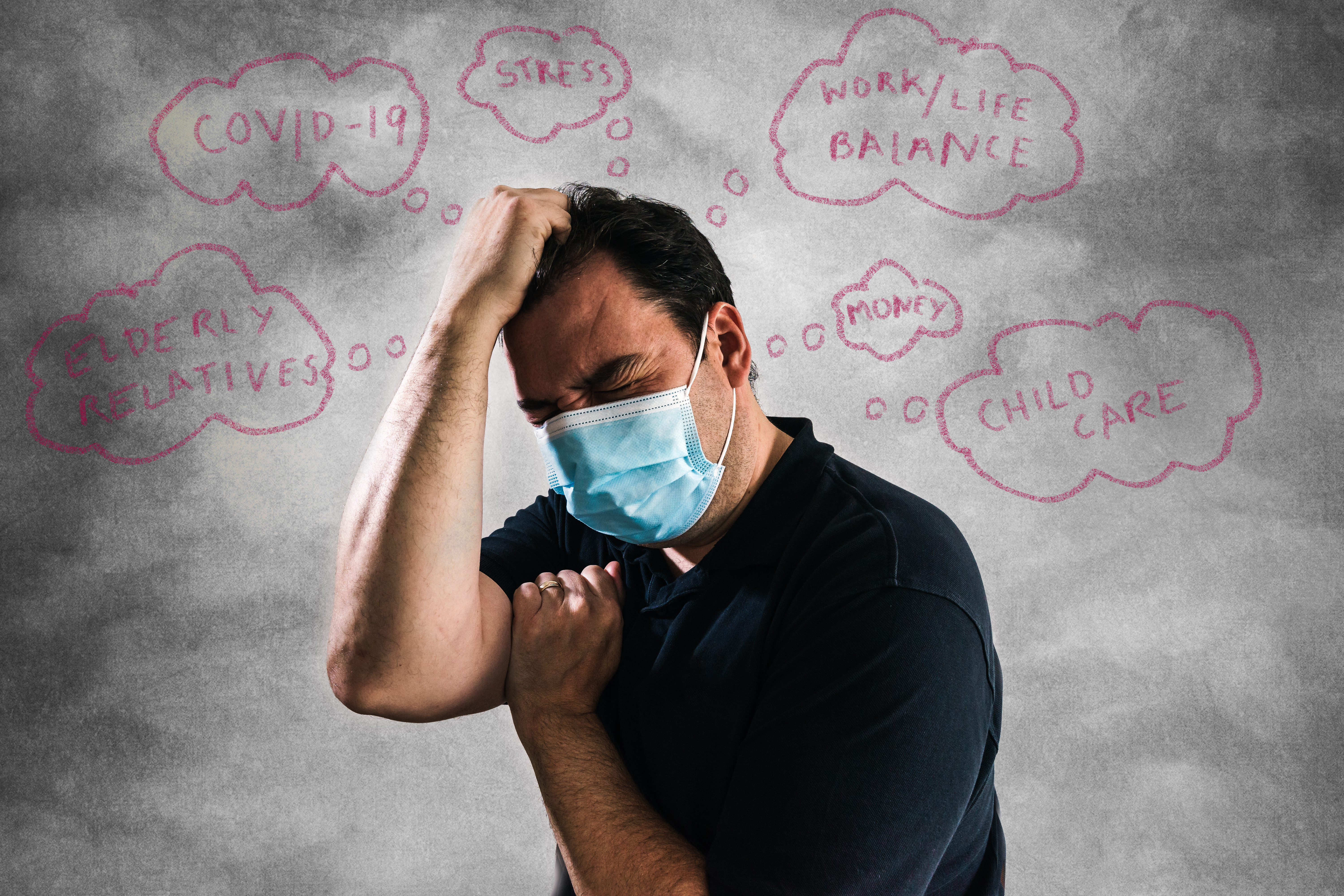 Photo of a middle-aged man in a navy polo shirt and blue surgical mask, eyes closed tight, pressing one fist to his head and the other to his shoulder. On a gray background behind him, a series of thought bubbles include the phrases, "elderly relatives," "COVID-19," "stress," "work/life balance," "money," and "child care."